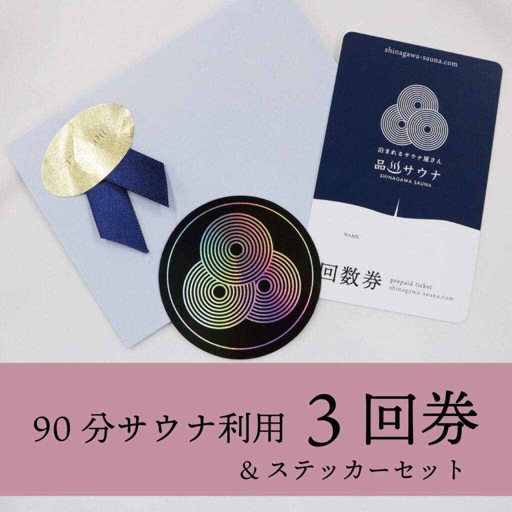 品川サウナの90分サウナ利用3回券＆ステッカーセット。薄紫色の封筒に金色のシール、紺色の回数券カード（品川サウナロゴ入り）、ホログラム加工のオリジナルステッカーがセットになっている