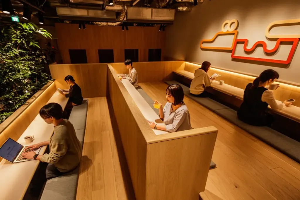 ワーキングスペースで6人が作業や飲み物を楽しんでいる