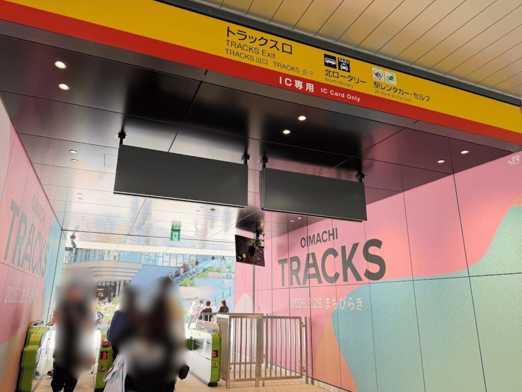 JR大井町駅「トラックス口」の改札。黄色い案内サインに「トラックス口 TRACKS Exit」「IC専用 IC Card Only」と表示され、奥にピンク基調の壁面と『OIMACHI TRACKS』のロゴ。改札の先が施設へ直結している。