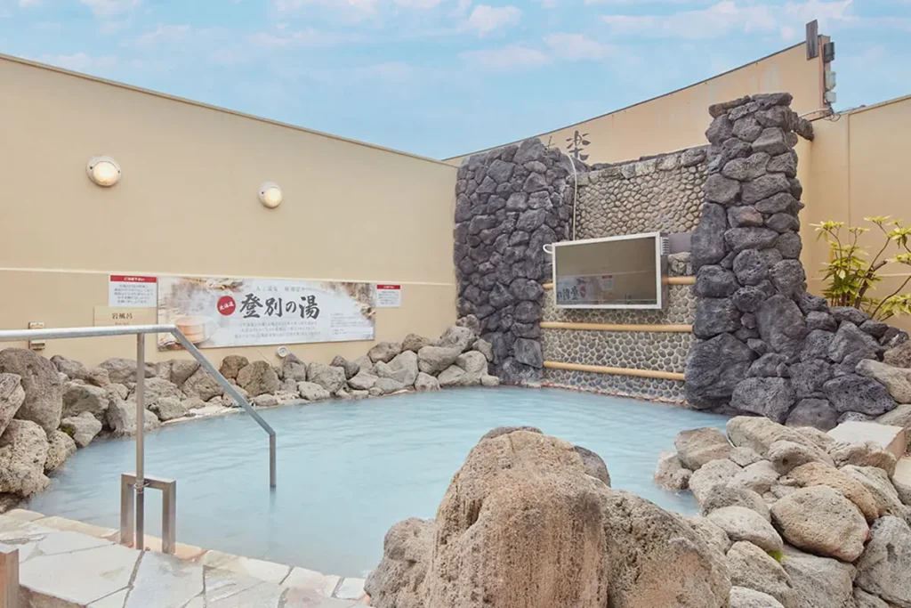 ととのいの郷 秦野湯花楽の名湯めぐり露天風呂。岩に囲まれた湯船に登別温泉を再現した乳白色のお湯がたたえられている