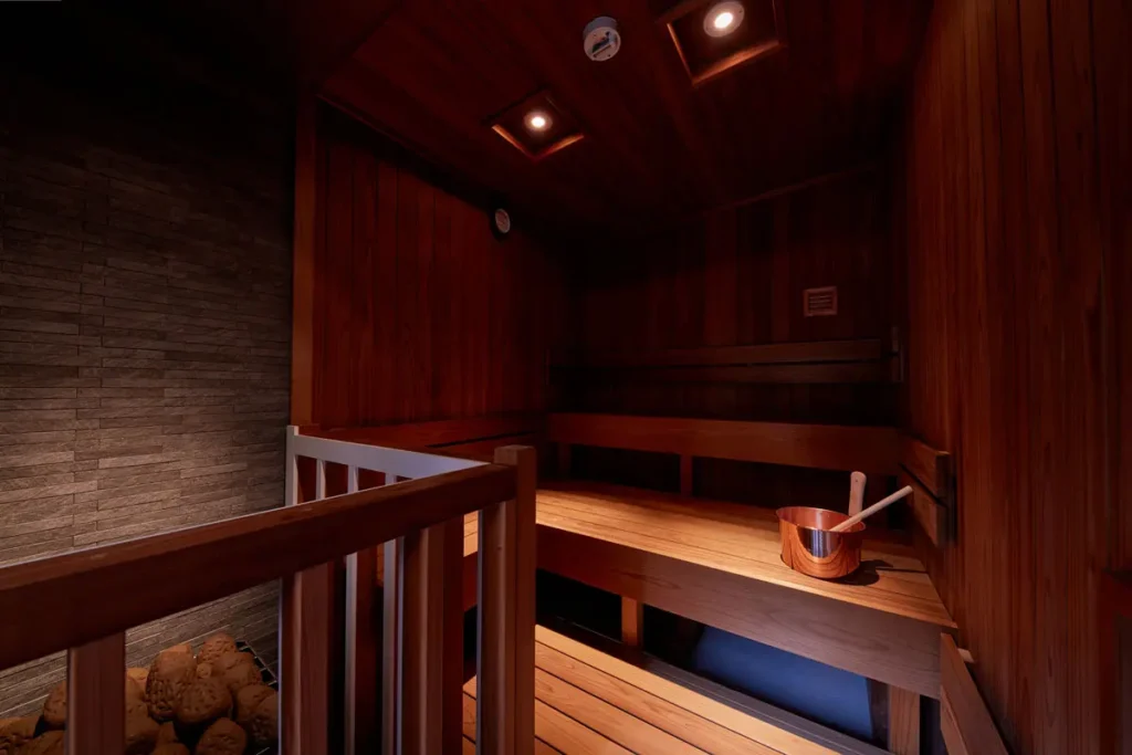 ととのいの郷 秦野湯花楽の瞑想サウナ。落ち着いた照明の木造室内にサウナストーンと銅製のラドルが置かれている