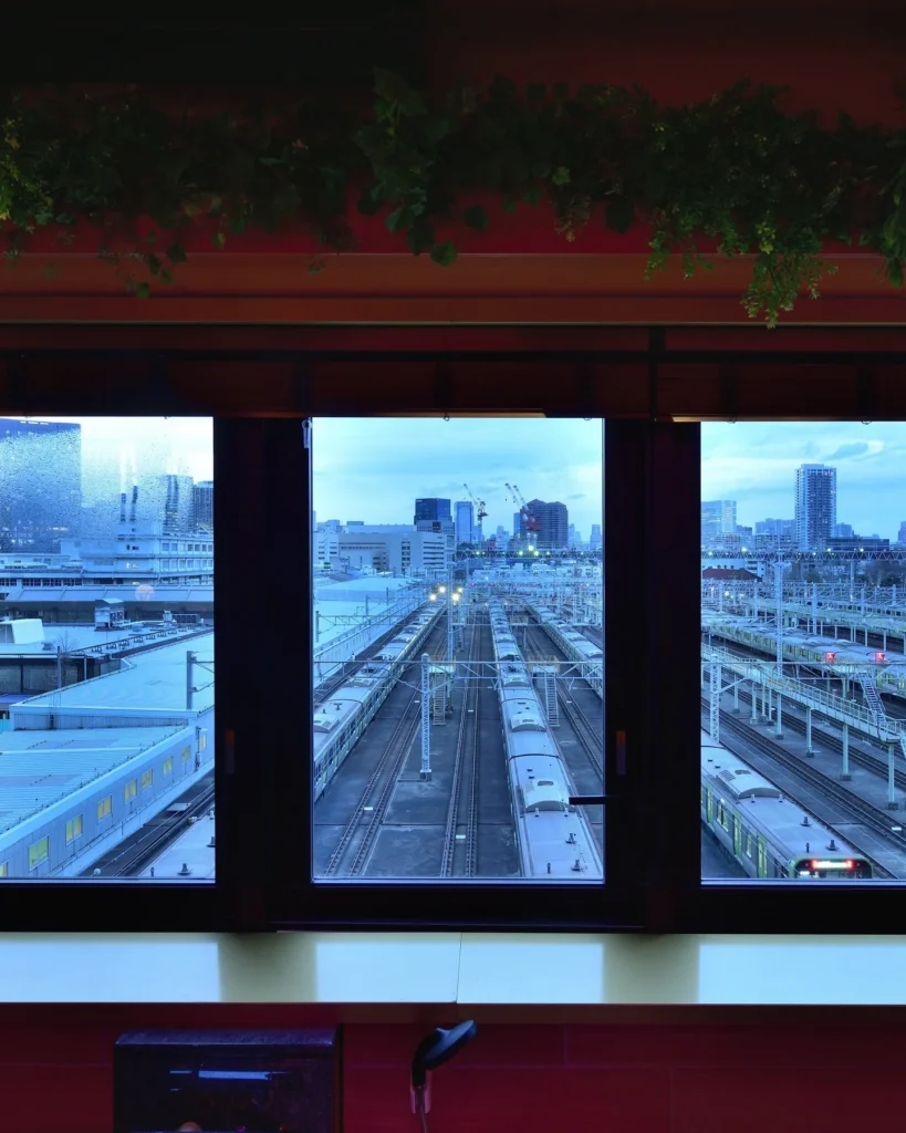 トラムサウナ内の3連窓から見える東京総合車両センター（車両基地）のトレインビュー。サウナの中から本物の電車が眺められる