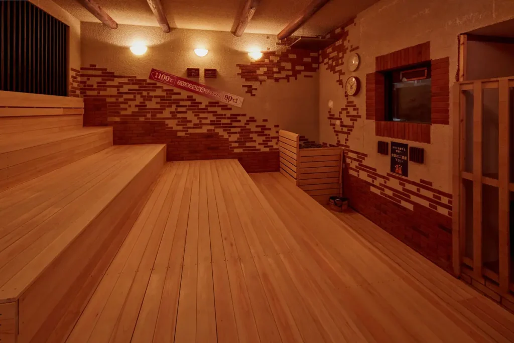 ととのいの郷 秦野湯花楽のタワーサウナ。レンガ造りの壁と4段のベンチが広がる室内に100℃の温度表示が掲げられている