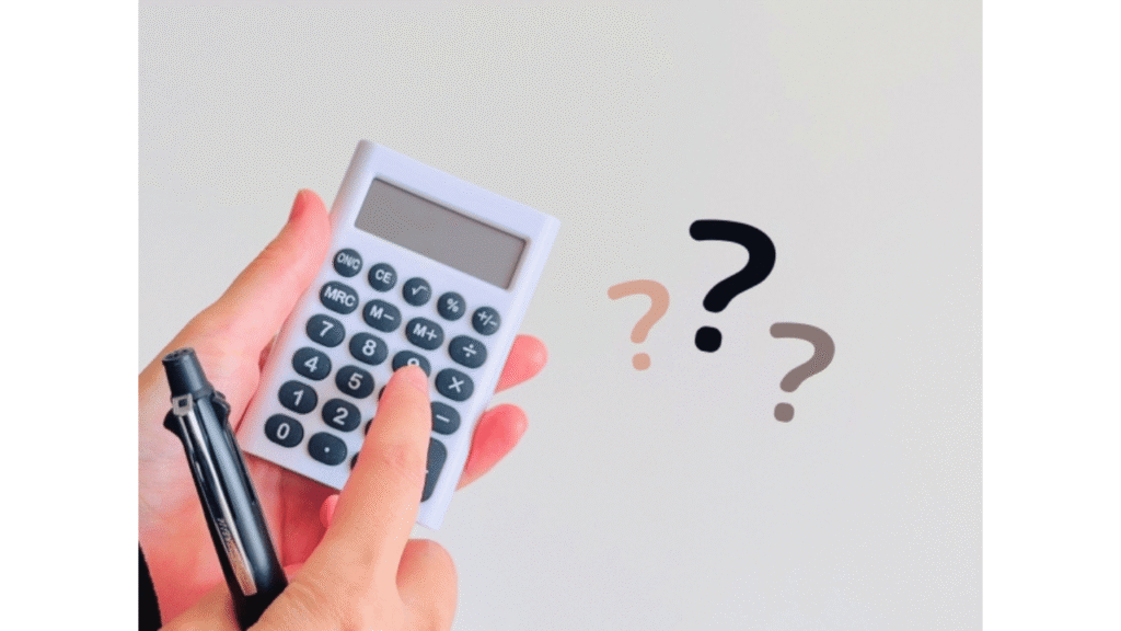 電卓と3つの「?」とペン、左手で電卓を持ち右手の人差し指で電卓のボタンを押している