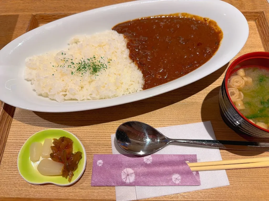 木製トレイに盛り付けられたビーフカレーセット。白い楕円皿にライスとカレールー、赤い漆器の味噌汁、緑の小皿に福神漬け。桜柄の紙ナプキンに箸とスプーンが添えられている