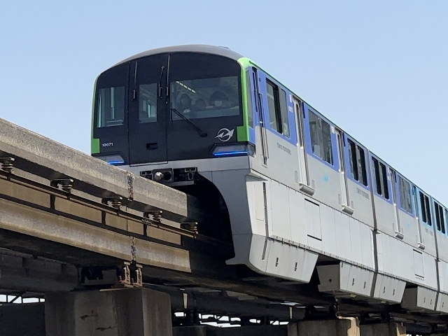 高架の駅ホームに停車する白い東京モノレールの車両