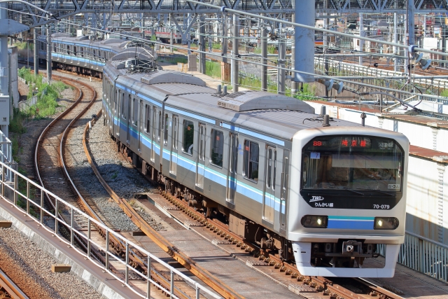 カーブした複数の線路が並ぶ駅に停車する濃紺の通勤電車