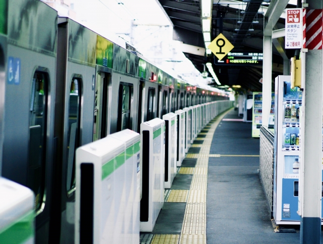 駅のホームに停車する、緑の帯が入った普通列車グリーン車