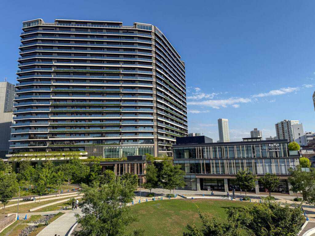TOTOPA都立明治公園店が入るガラス張りの建物外観。青空と植栽を背景にした、緑に囲まれたモダンな低層の建物