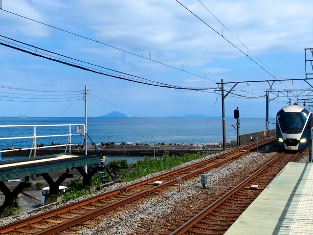 海を背景に、海沿いの駅へ進入するサフィール踊り子