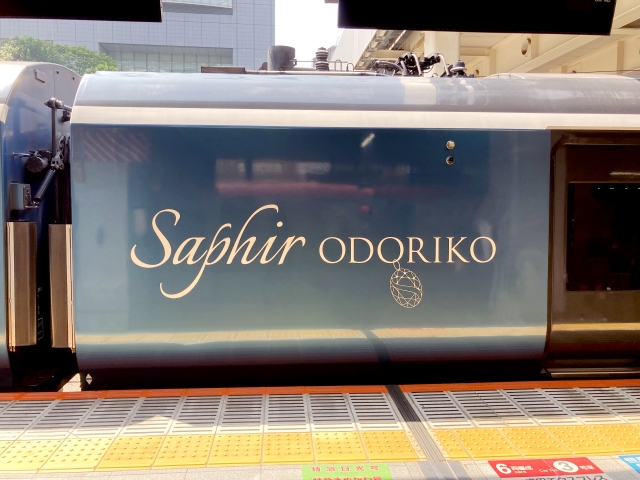駅のホームに停車する車体側面に描かれた「Saphir ODORIKO」のロゴ