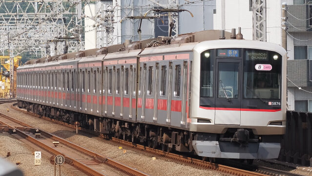 元町・中華街行きの表示を掲げて走る、赤いラインが入った東急東横線の8両編成の電車