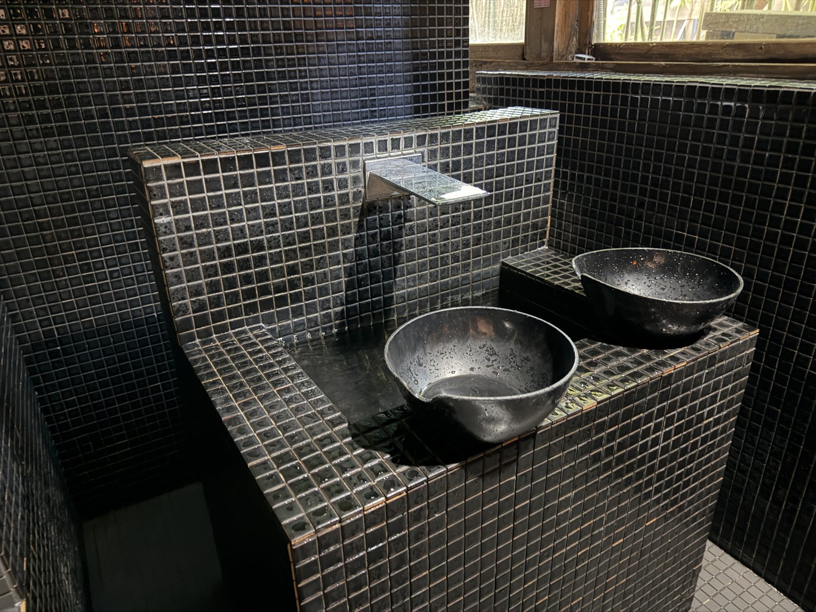 黒いタイル壁の前にかけ湯用ボウルが並ぶKIWAMI SAUNA本店の水風呂前