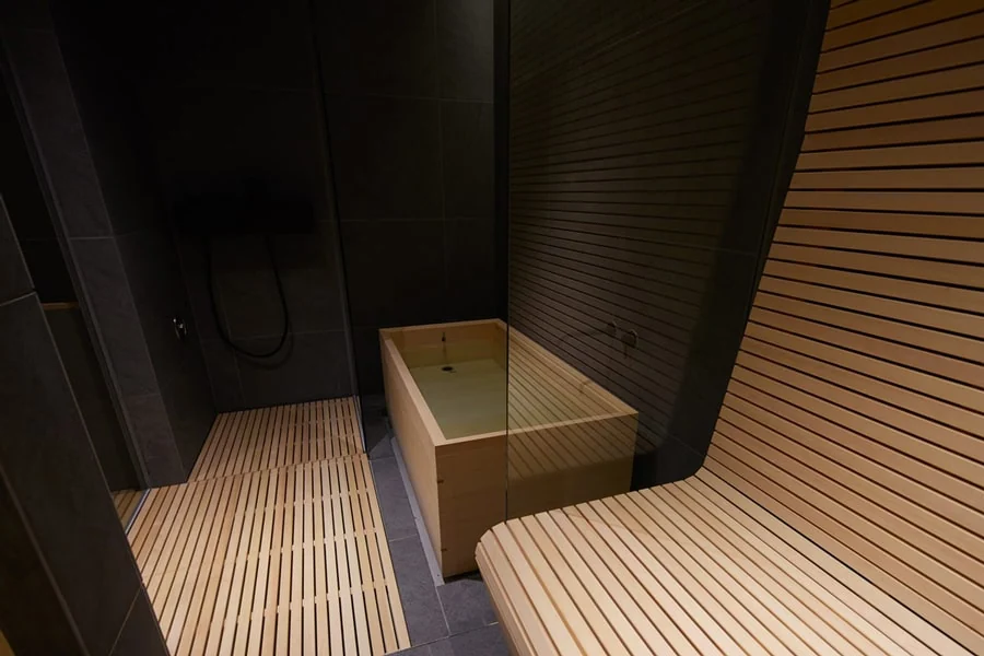 個室＆シェアサウナ KUUMAの木製水風呂と休憩ベンチ