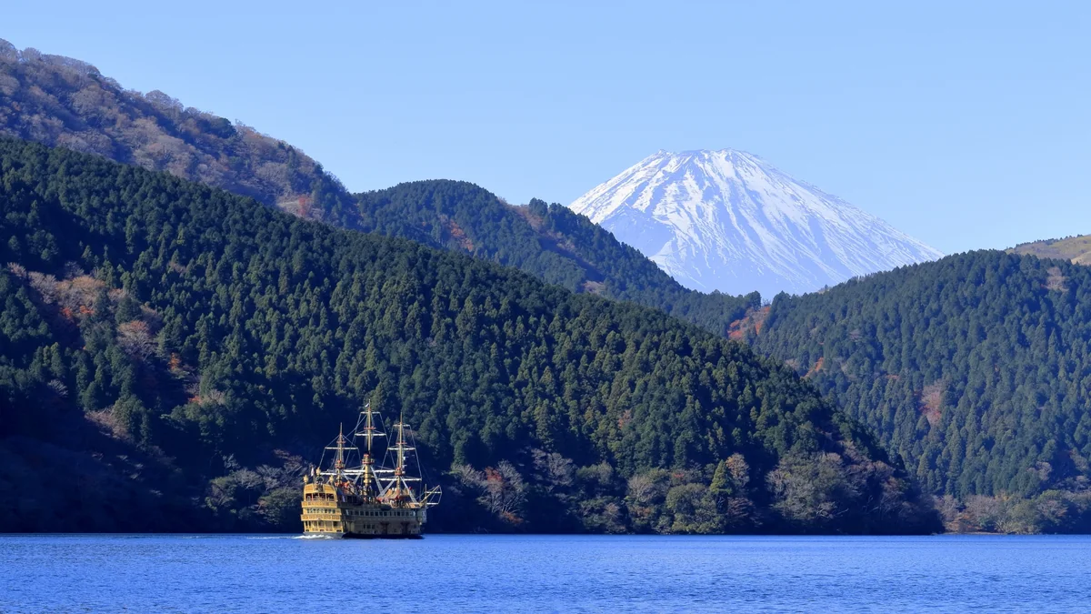 芦ノ湖を進む海賊船と雪化粧した富士山