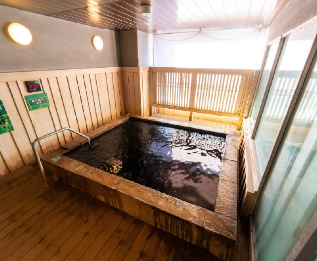 RAKU SPA Station府中の露天風呂 黄昏 窓際の浴槽に黒褐色の天然温泉をたたえるRAKU SPA Station府中の露天風呂 黄昏