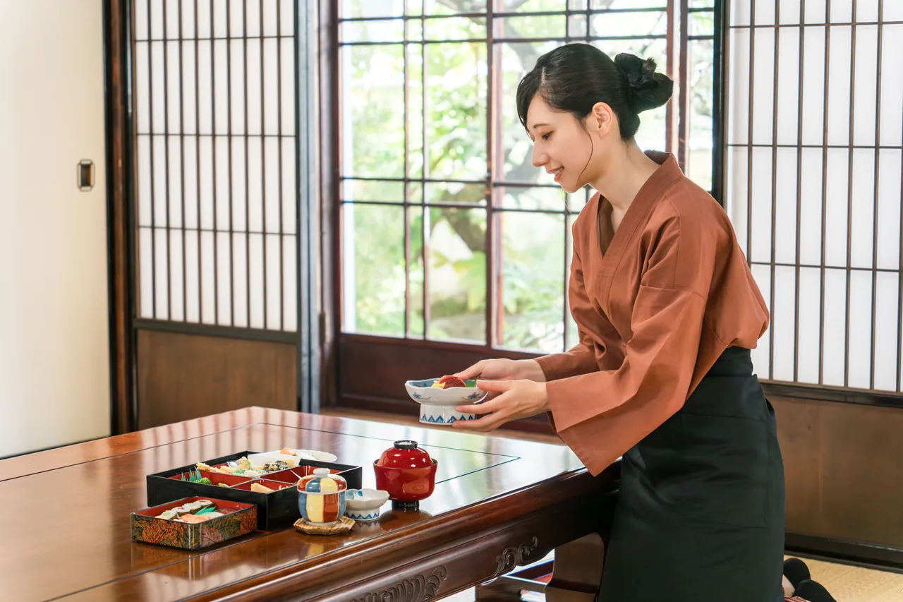 旅館の客室で料理を配膳するリゾートバイトスタッフのイメージ
