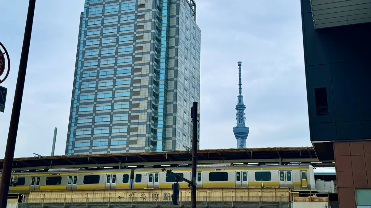 JR錦糸町駅を走る黄色い総武線車両と東京スカイツリー