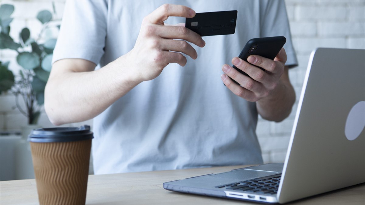 クレジットカードを見ながらスマートフォンで決済情報を入力する人