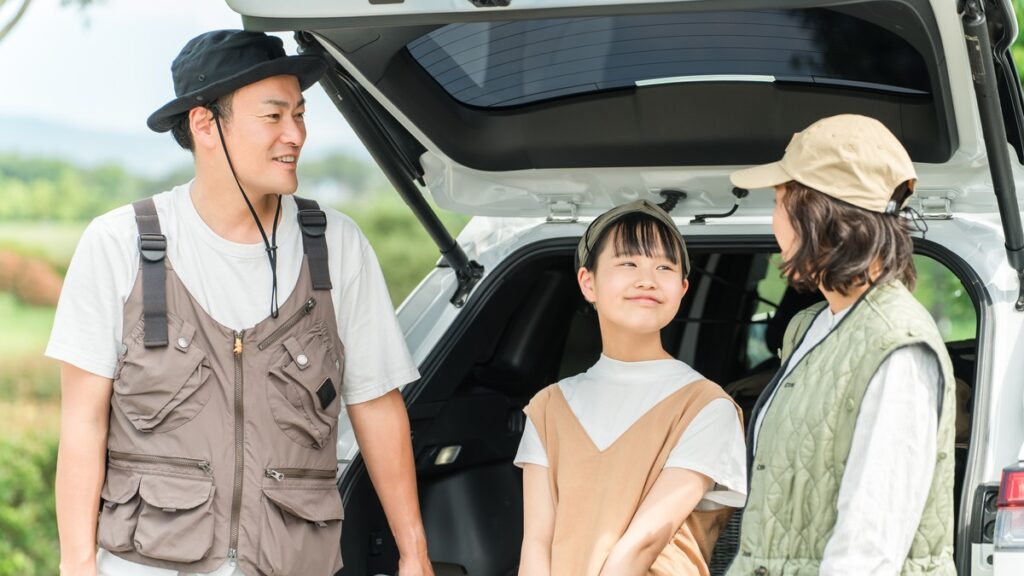 旅行先で車のトランクを開けて休む家族のドライブ風景