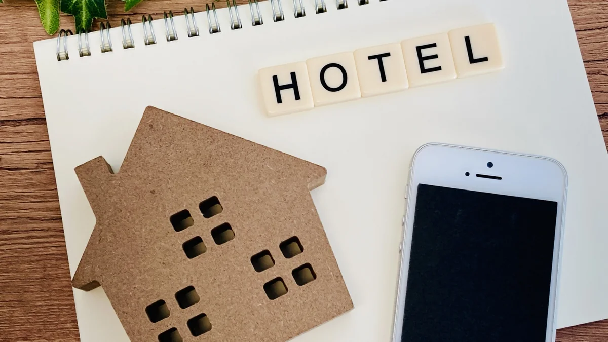 HOTELの文字と宿の形、スマートフォンを並べたホテル・旅館予約のイメージ