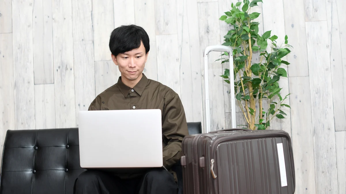 スーツケースの横でスキー場の短期バイト求人を探すイメージ