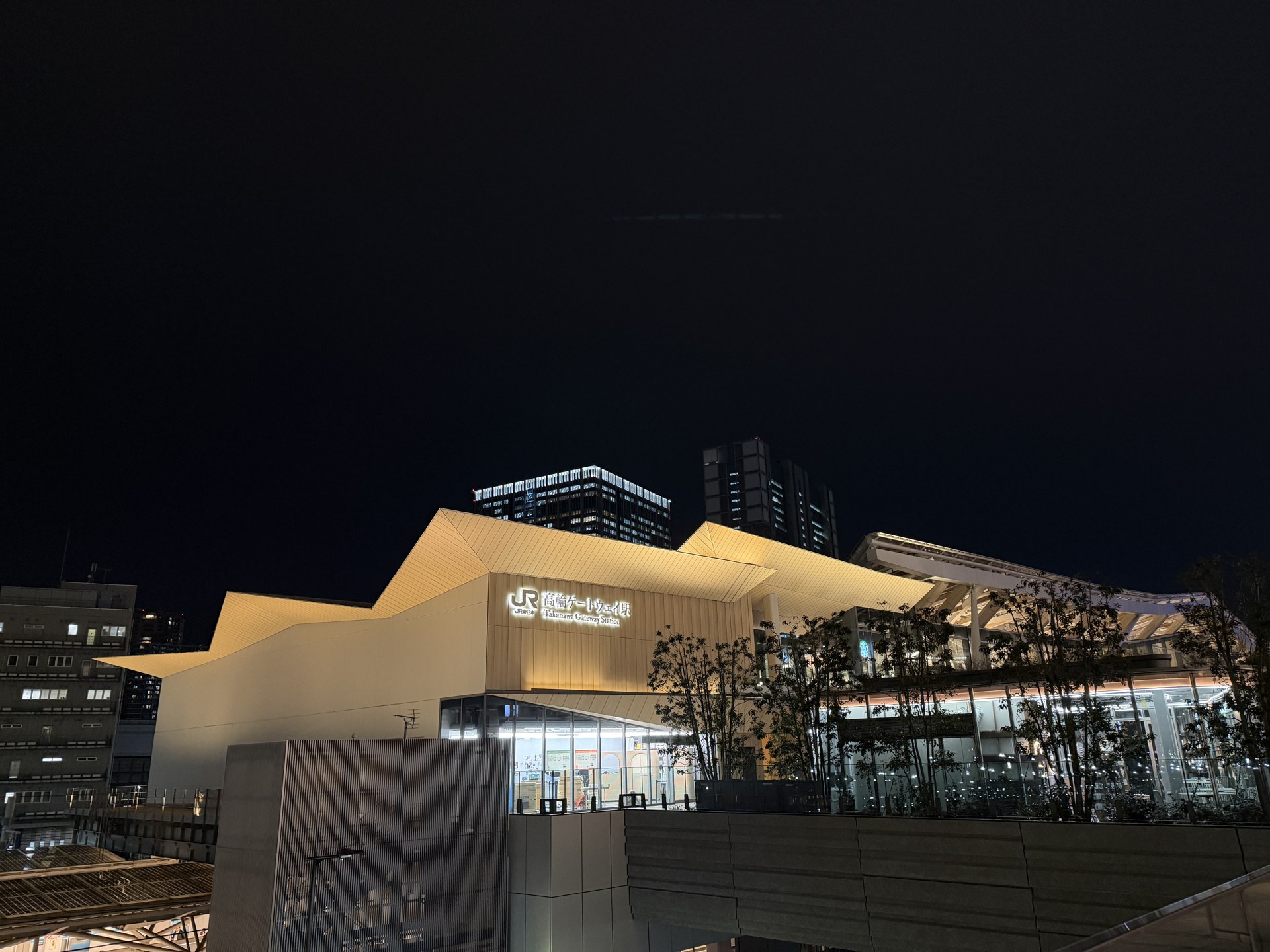 夜に照らされた高輪ゲートウェイ駅の白い折り紙状の屋根と駅舎