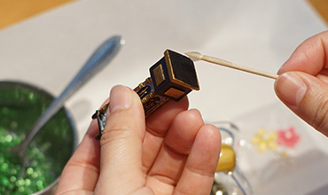 小樽オルゴール堂の制作体験で飾りの小物に接着剤を付ける手元